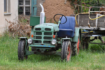 Obraz premium An old and rusty tractor with a trailer nearby the village Bernburg-Germany.