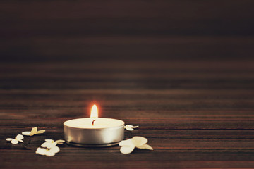 Obraz na płótnie Canvas Burning candle and white flowers on wooden background
