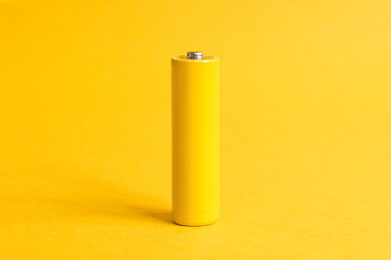 Single yellow battery on a yellow pastel background
