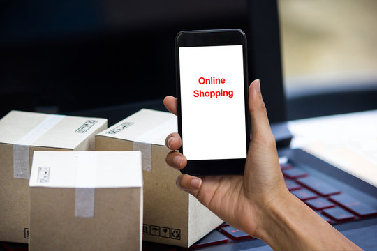 Online shopping concept e-commerce delivery buying service. square cartons shopping on laptop keyboard, showing customer order via the internet on smartphone.