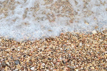 Sea water foam and pebbles on the beach