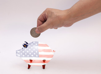 man putting coin into piggy bank with USA flag