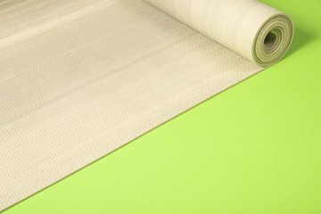 Yoga mat on green background with copyspace.
