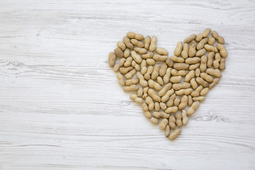 Peanuts in heart shape, top view. Flat lay. From above. Copy space.