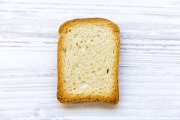 Single toast over white wooden background, top view.