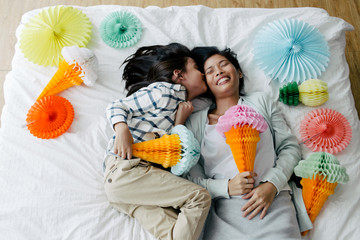 Asian mother and kid having fun playing with ice-cream cone shaped tissue paper lantern decoration in the bedroom