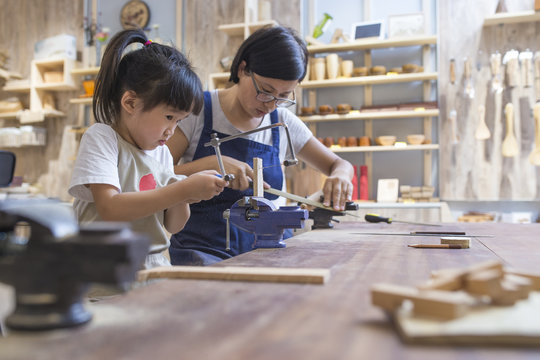 Asian womant with her kid doing carpenter job in the studio