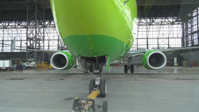 Passenger plane pulled out of the hangar on the tarmac. Tug pulls the plane out of the hangar. After repair, the aircraft is pulled out of the hangar. The plane is towed on the runway. 4K