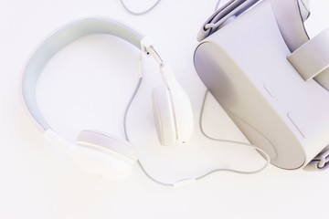 Stylish headphones and VR headset on a white table top view. 