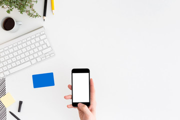 Man holding smartphone during internet payment over office desk.