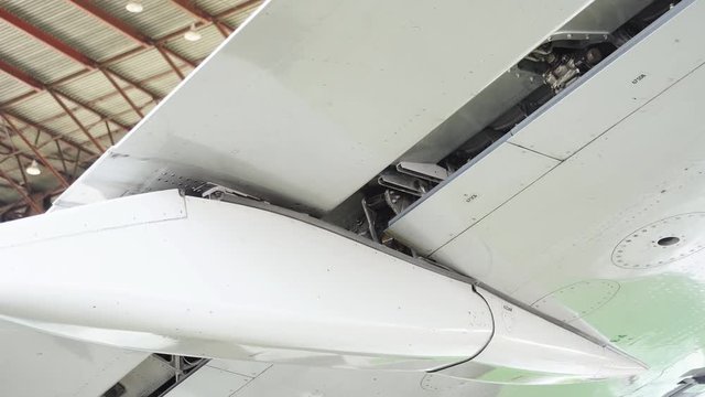 Repair of the aircraft. Repair the flap of the wing of a passenger plane. The pilot checks the wing flap. The plane is in the hangar to repair. The white plane is being repaired in the hangar. 4K