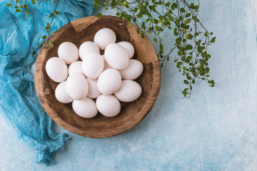 Fototapeta na wymiar White Eggs in a Brown Wood Bowl against a Turquoise Background