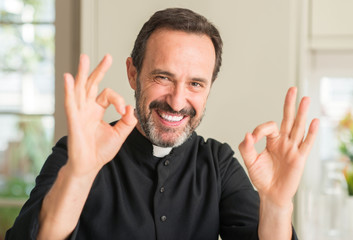 Christian priest man doing ok sign with fingers, excellent symbol