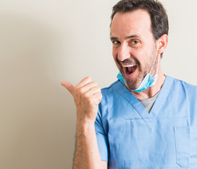 Senior doctor man using mask pointing with hand and finger up with happy face smiling