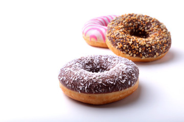 Assorted doughnuts in the glaze, colorful sprinkles and nuts on a white background.