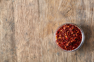 Red hot chilly pepper in transparent glass bowl vintage wooden background, close-up, top view, selective focus.