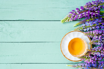 Light blue wooden background with white cup of herbal tea