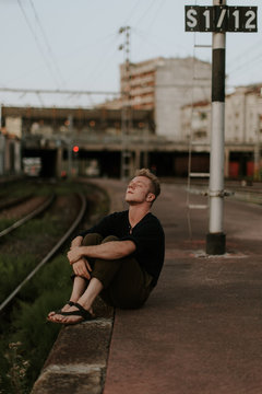 young man sitting in te border of the railway