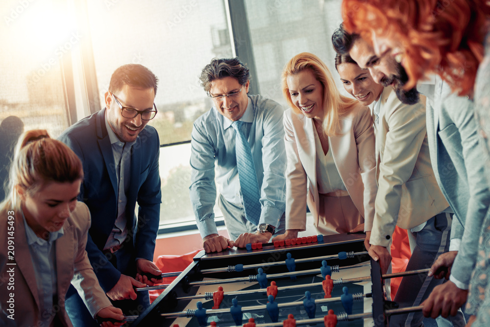 Poster Colleagues playing table football in modern office