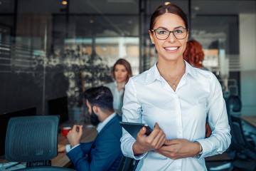 Business woman using tablet in front of her colleagues in the office
