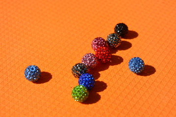 On an orange background with a structure there are chaotically beautiful multicolored balls with...