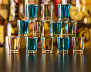 Popular blue drink shot kamikaze on the background of the bar with bottles, a refreshing drink