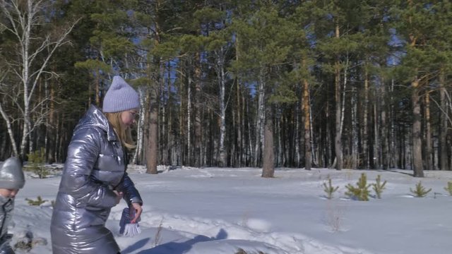 Beautiful woman and small child walking in winter forest with of husky dog. Happy young mother with daughter in the winter park with huskies dog. Friendship pet and human. Siberian husky dog in snow