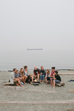 Multi generational family hanging out together around fire on the beach