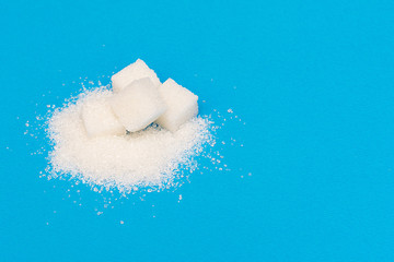 White sugar in cubes on a blue background. An empty place to write a text.