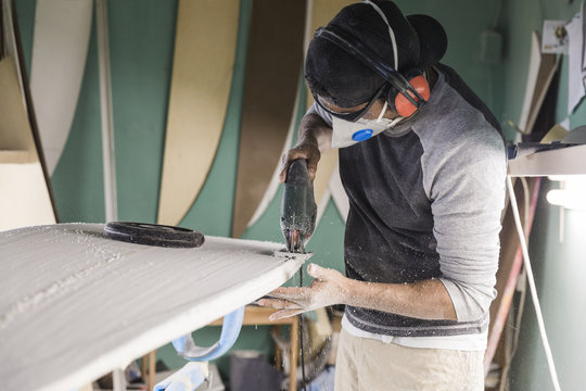 Man shaping surfboard with electric jigsaw - Powered by Adobe
