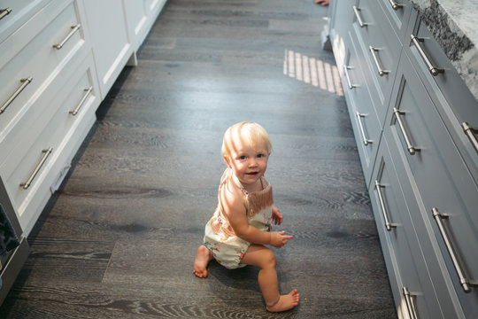 Happy one year old girl crawling on kitchen floor