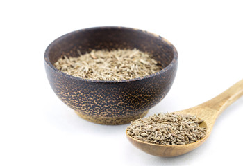 dried cumin in a wooden spoon and bowl wood on white background