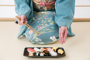 寿司を食べる着物姿の女性
