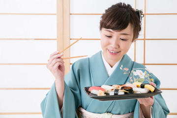 寿司を食べる着物姿の女性
