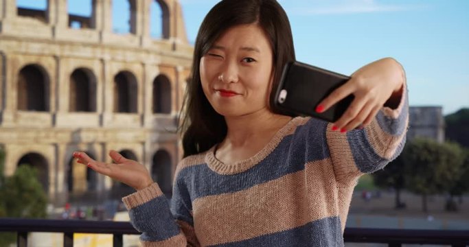 Casual millennial woman using smartphone to take selfie in front Colosseum in Rome Italy, Close up of happy young Asian women taking selfie with cell phone camera in ancient European city, 4k
