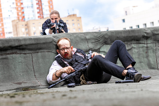 Man And Woman Dressed As Special Agnets Or Killers With Rifles On The Roof