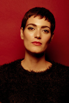 Beautiful and confident short haired woman portraits in her 30s shot in studio isolated over red background