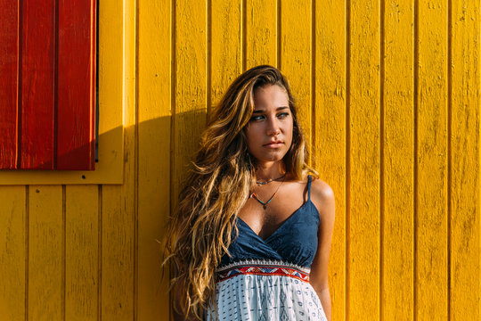 Gorgeous blond woman on a wooden yellow wall