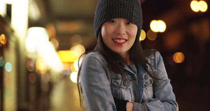 Freezing millennial woman trying to warm up with mittens and rubbing arms at metro, Close up of young Asian female using beanie and gloves to keep warm at train station, 4k