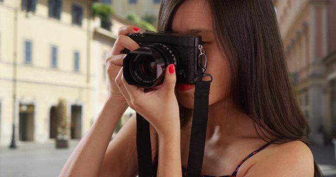 Portrait of young female tourist in her 20s taking photographs with camera in Florence Italy, Close up of millennial photographer using dslr camera to take photos in European city, 4k
