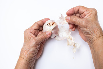 Senior woman's hand peeling Garlic or Allium sativum  isolated on white background