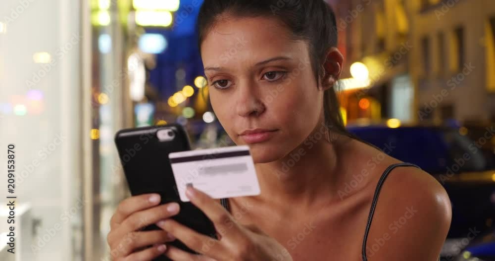 Wall mural close up of young woman on city street shopping online with card and smartphone, pretty caucasian fe