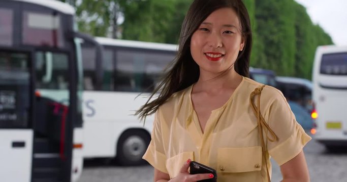 Chinese woman tourist on bus tour smiling while at rest stop on vacation, Asian Millennial female on trip smiles at camera, 4k