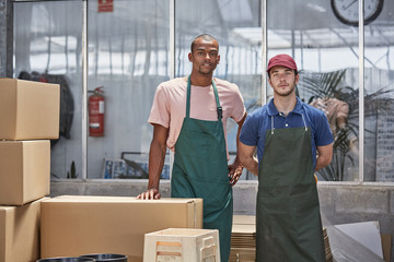Confident Workers Standing By Cardboard Boxes In Greenhouse