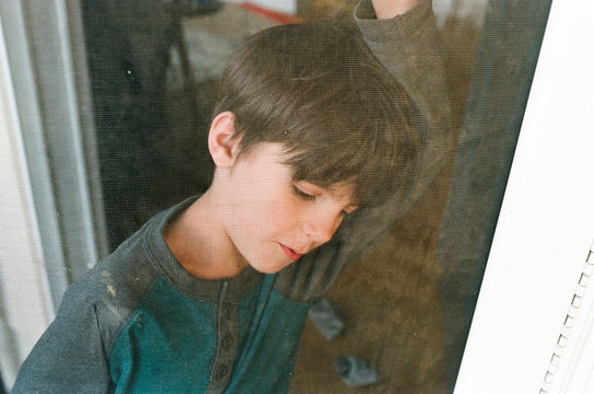 boy leans against screen door