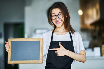 happy waitress holding blank chalkboard sign