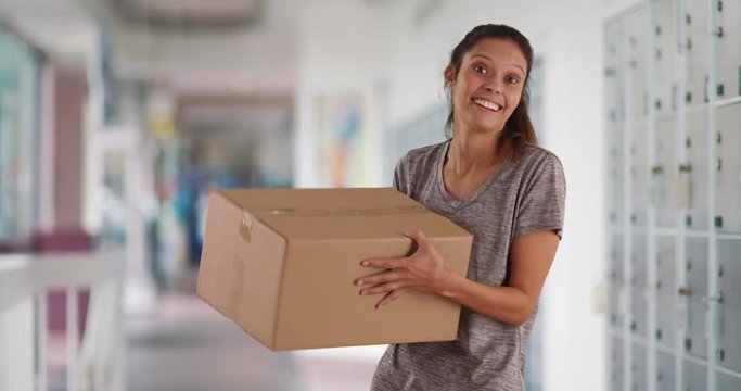 Cheerful young woman at post office tossing cardboard box into air, Pretty Caucasian girl picking up delivery box excited to open it, 4k