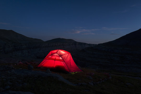 Illuminated red tent during the night on mountains