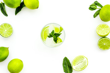 Fototapeta na wymiar Refreshing mojito cocktail. Slices of lime, mint, glass with ice cubes on white background top view space for text