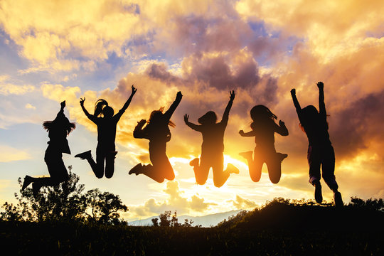 silhouette of friends girls group jumping playing at sunset time